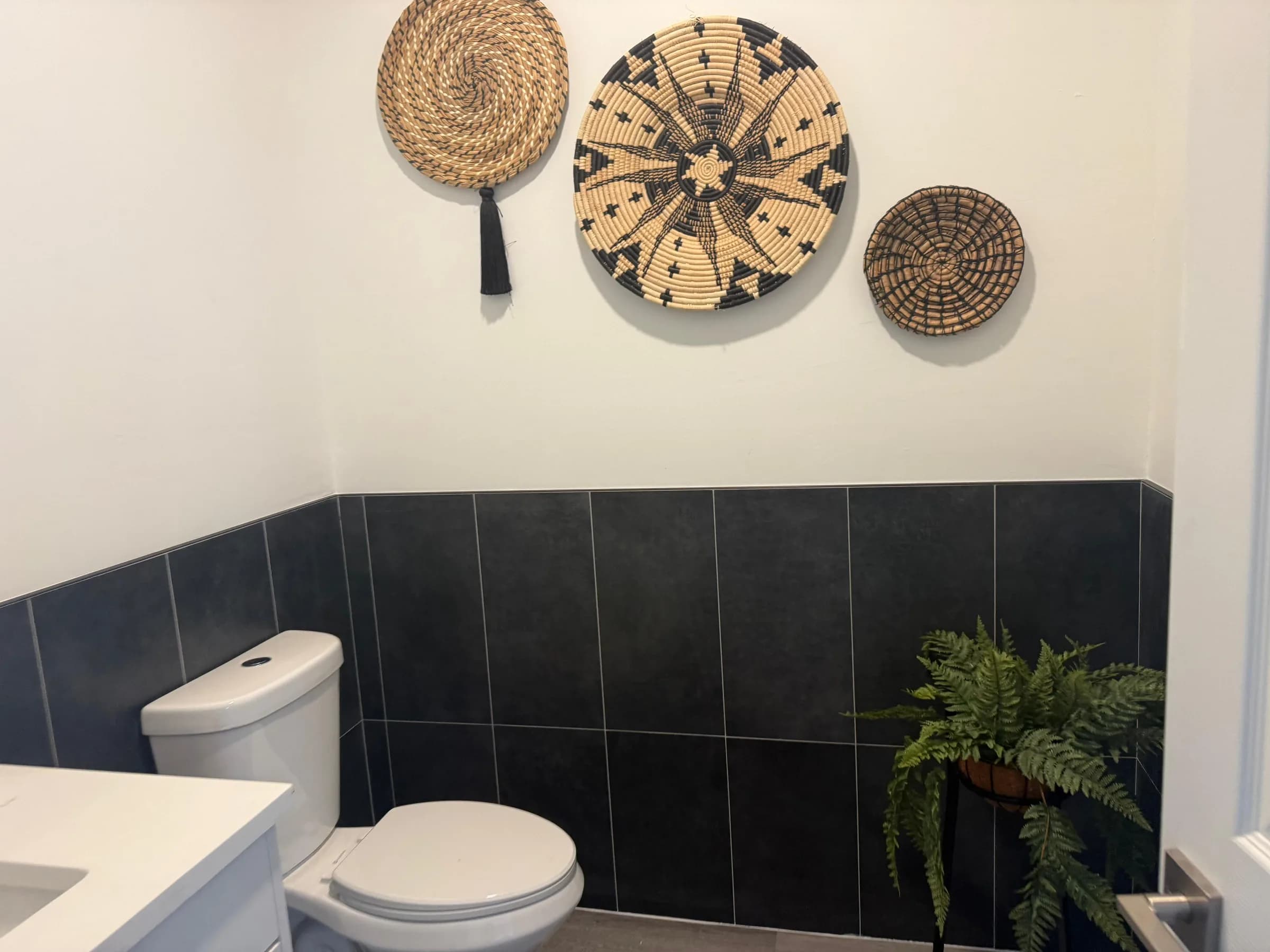 Powder room with dark tile wainscot and decorative wall finish